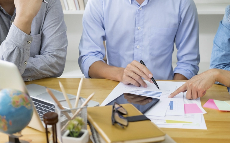 hombres y mujer mirando papeles y comentando